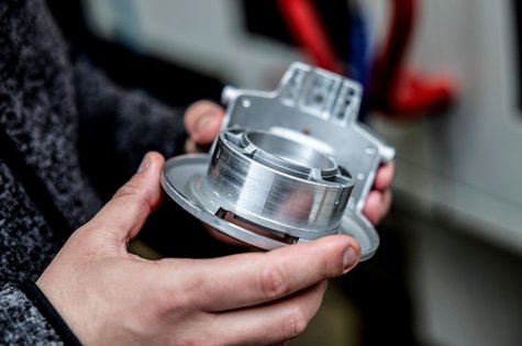 Männerhände halten Bauteil der Antriebstechnik in der Hand
