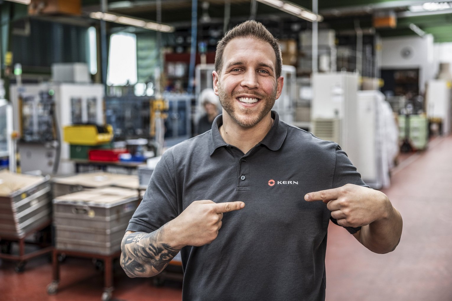 Kern Motion Technology employee portrait Employee points to logo on Kern Motion Technology T-shirt