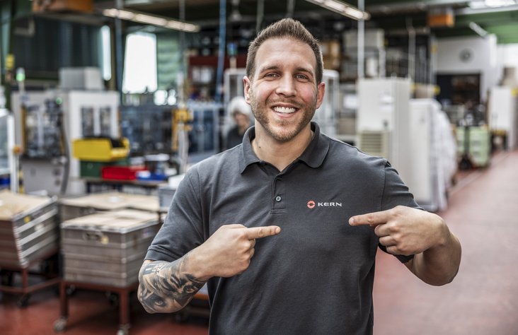 Employee points to logo on Kern Motion Technology T-shirt