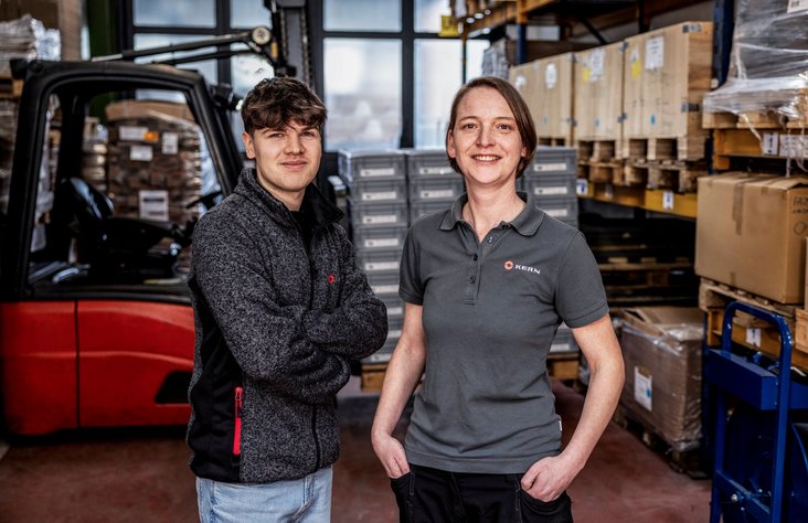 Two logistics employees smile at the camera.
